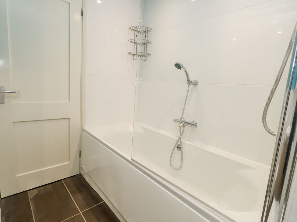 A bathroom with a shower and bathtub at Beachcombers, 13 Chesil House Bridport