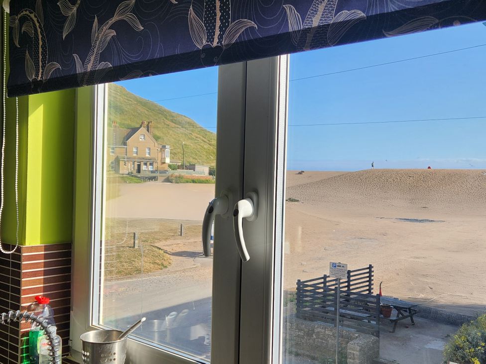 A kitchen window overlooking a beach at Beachcombers, 13 Chesil House, West Bay
