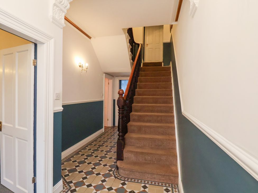 A hallway with a staircase and door at Kingfisher House Saltburn-by-the-Sea