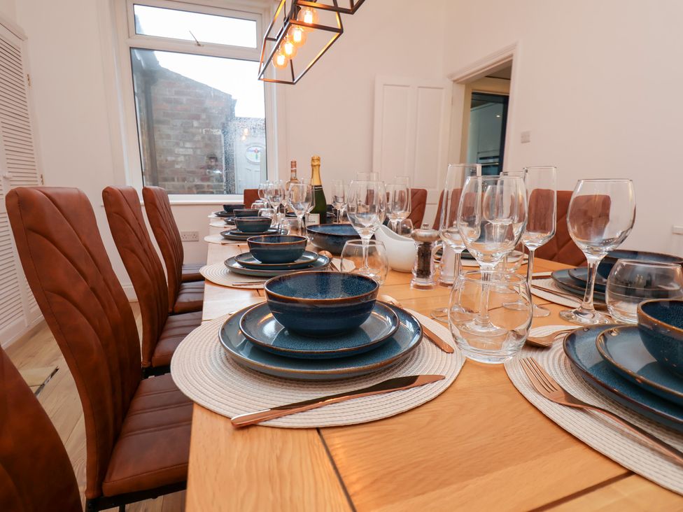 A dining room setup with plates and glasses at Kingfisher House Saltburn-by-the-Sea