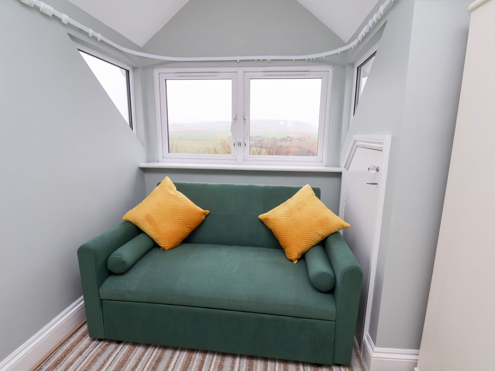 A snug with a green sofa and yellow cushions at Kingfisher House in Saltburn-by-the-Sea