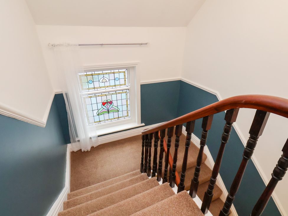 A staircase with a stained glass window at Kingfisher House Saltburn-by-the-Sea