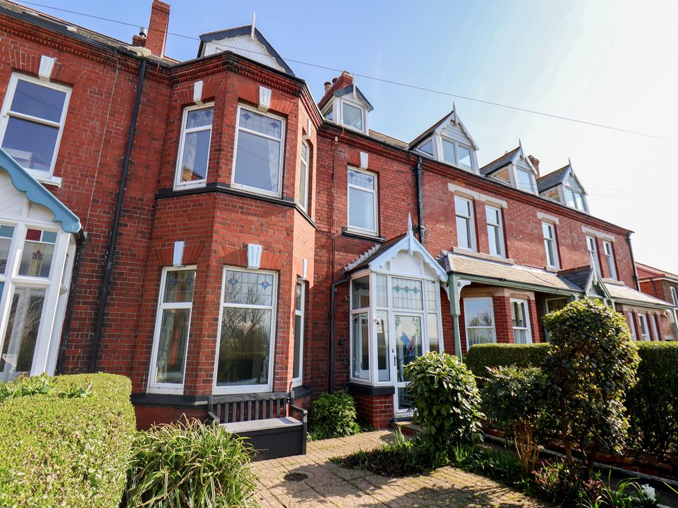 An exterior view of a brick house with windows and a garden at Kingfisher House in Staithes