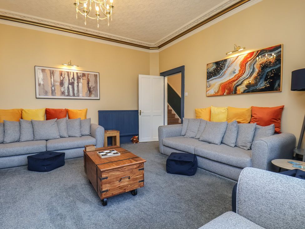 A living room with gray sofas and a wooden coffee table at Kingfisher House in Staithes