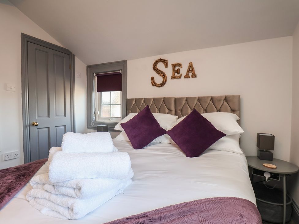 A bedroom with a bed and decorative pillows at Kingfisher House in Staithes