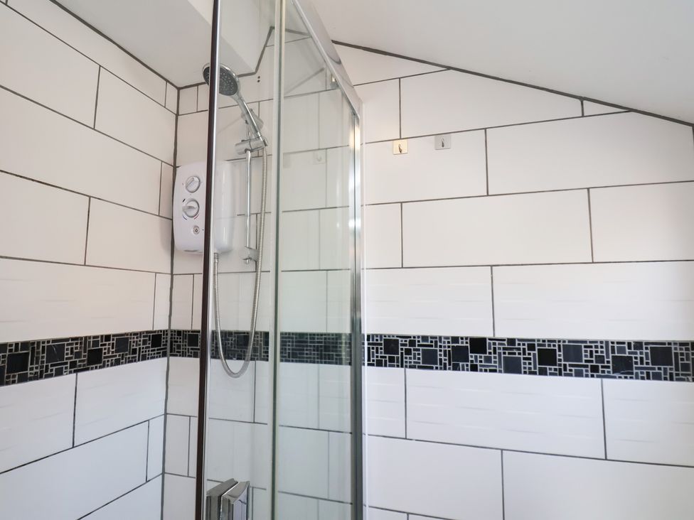 A bathroom with a shower and tile walls at Kingfisher House in Staithes