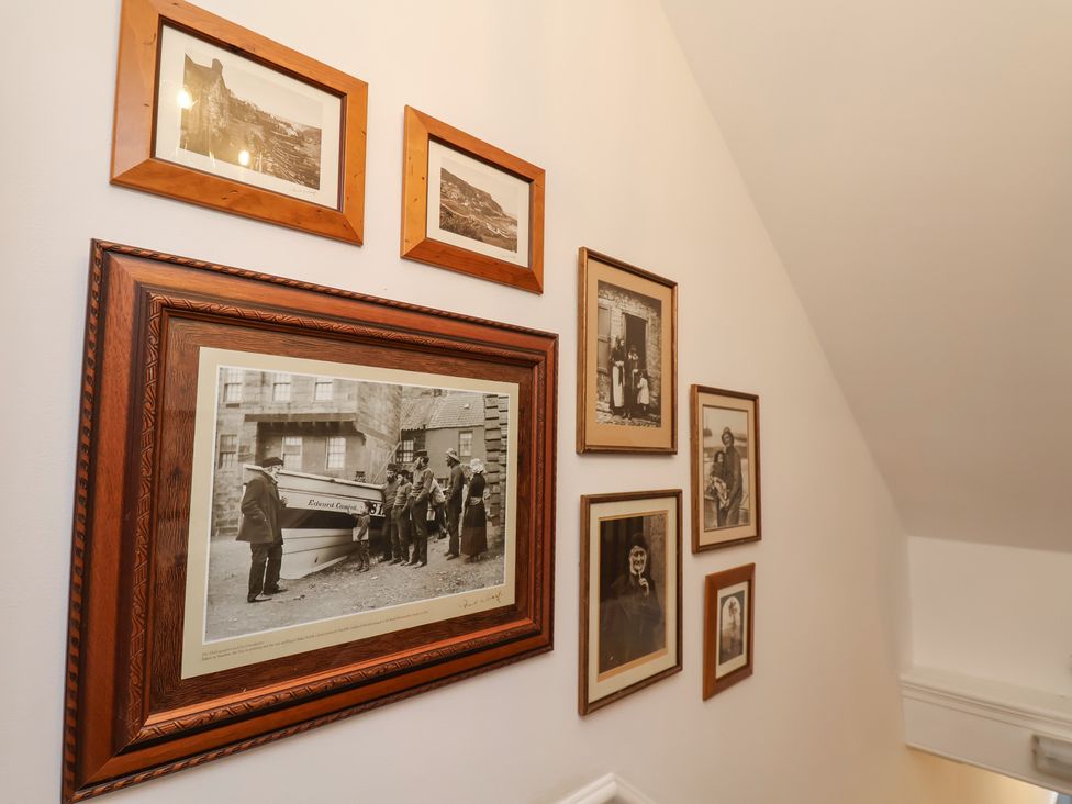 A wall with framed photographs in a staircase at Kingfisher House in Staithes