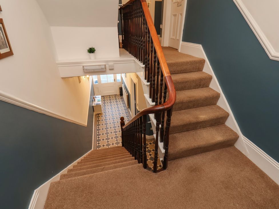 A staircase leading to a hallway with a door and tiles at Kingfisher House in Staithes