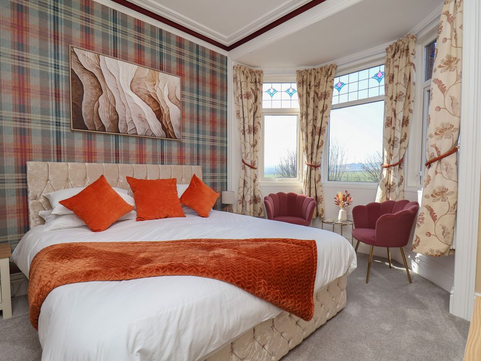 A bedroom with a bed and armchairs at Kingfisher House Staithes