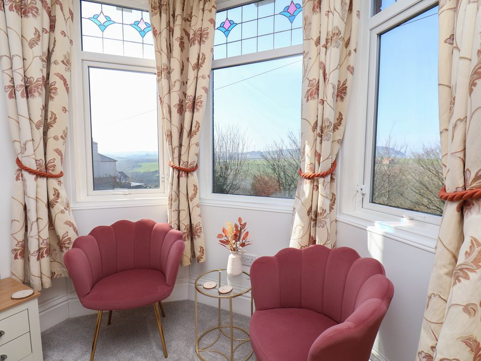 A snug with two pink chairs and a small table at Kingfisher House in Staithes