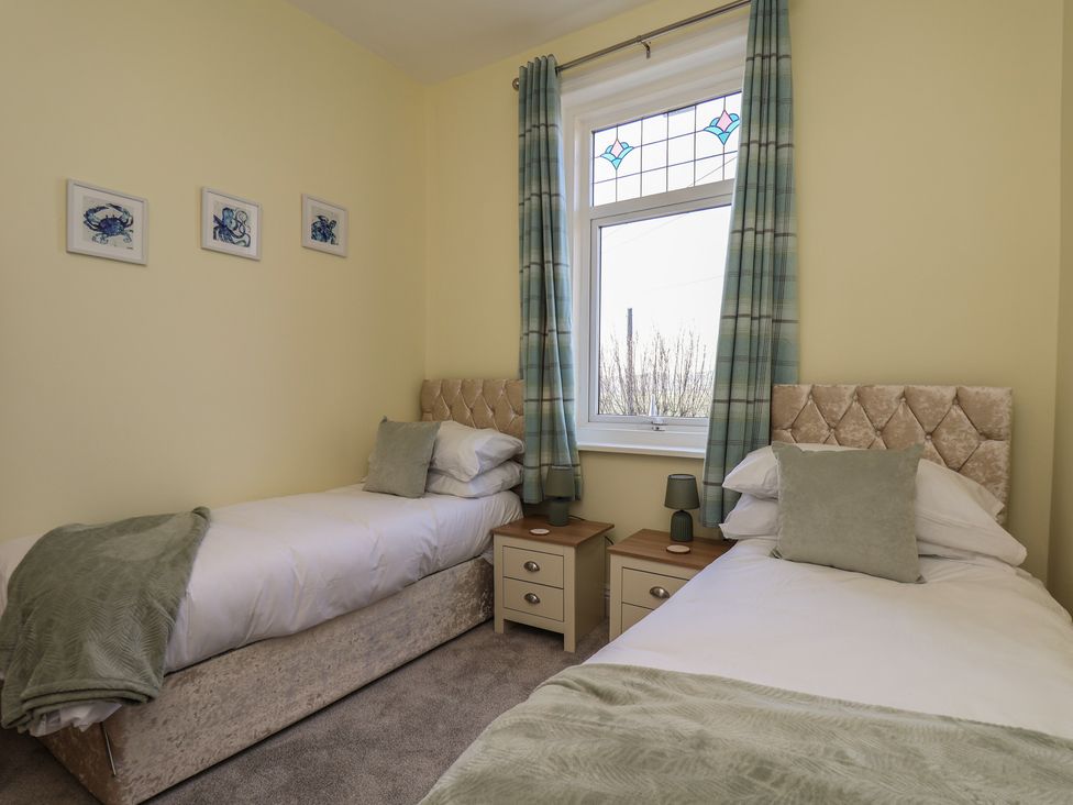 A bedroom with two single beds and a window at Kingfisher House in Staithes