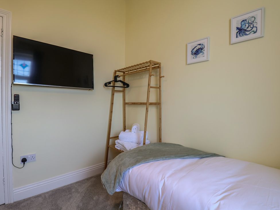 A bedroom with a bed, television, and clothes rack at Kingfisher House, Staithes