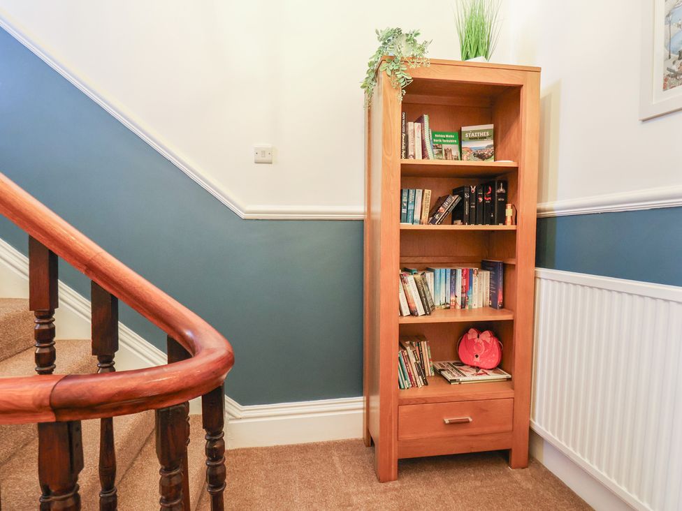 A bookshelf with books and a plant in a hallway at Kingfisher House in Staithes