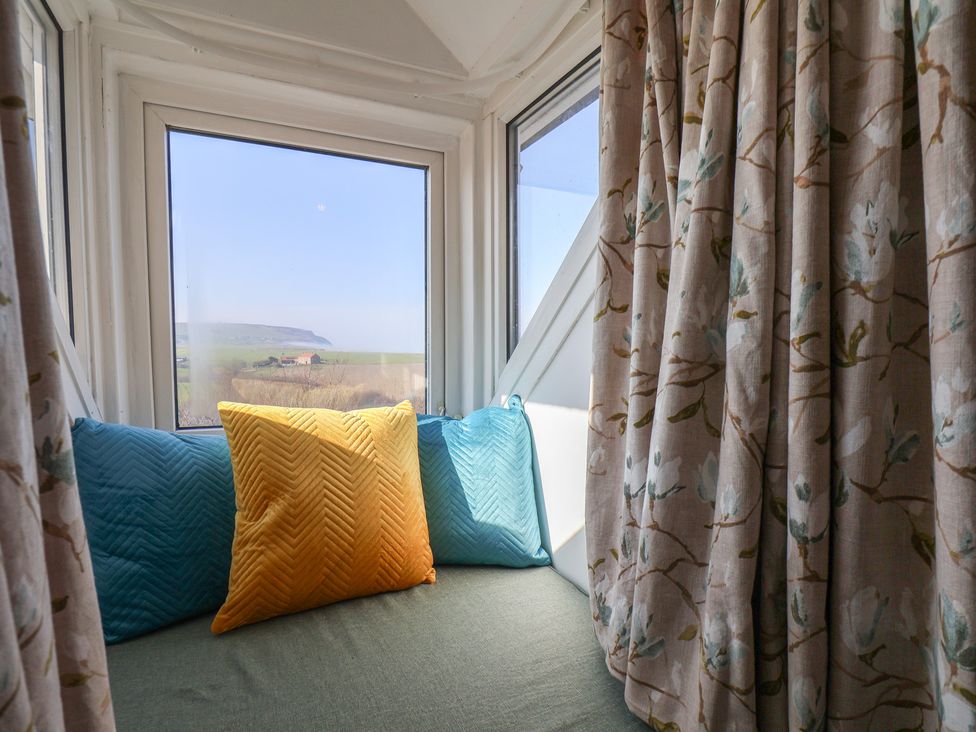 A sitting area with pillows and curtains at Kingfisher House in Staithes
