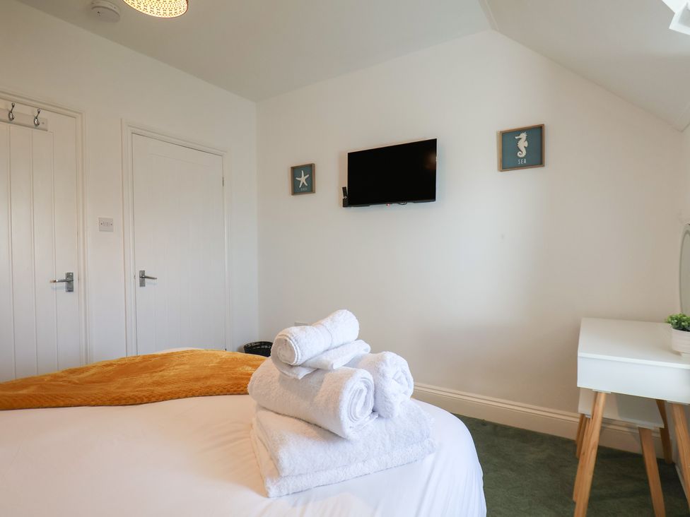 A bedroom with a television and towels on a bed at Kingfisher House in Staithes