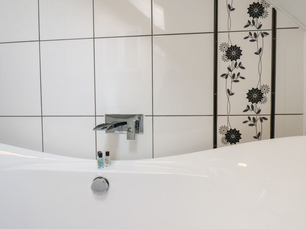 A bathroom with a bathtub and faucet at Kingfisher House in Staithes