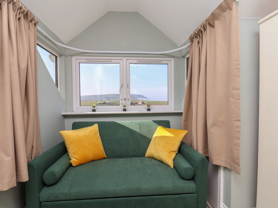 A snug with a sofa and windows at Kingfisher House in Staithes
