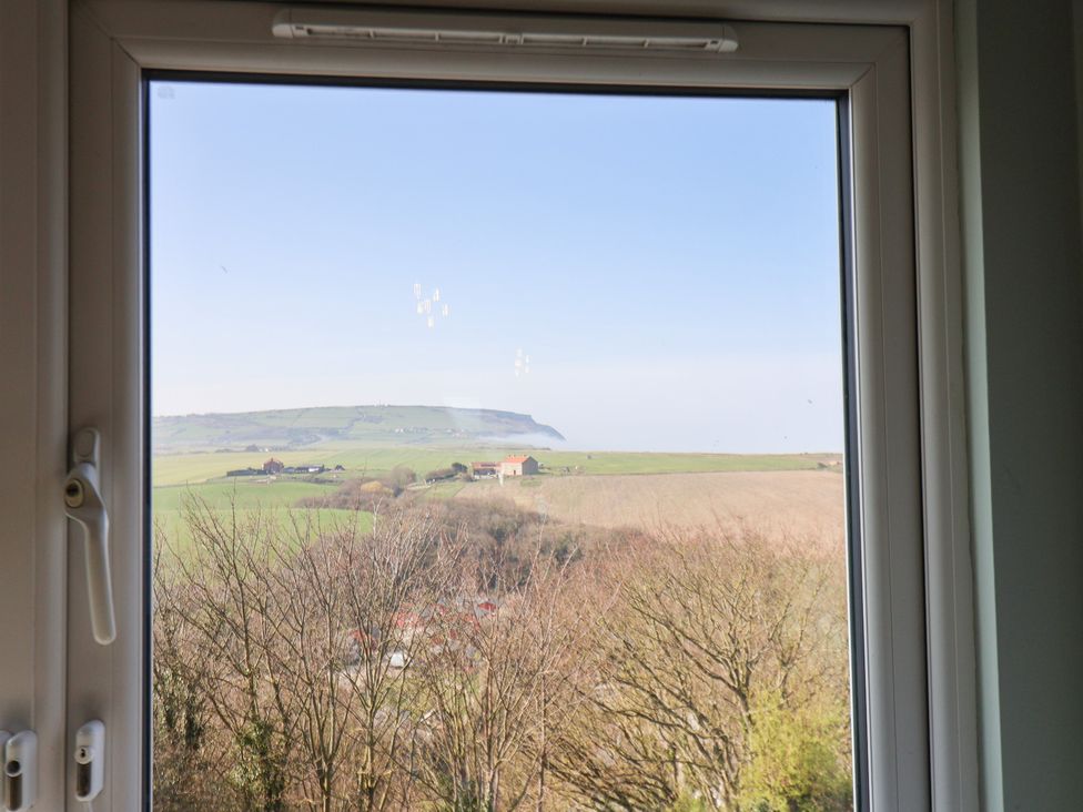 A view from a window showing fields and hills at Kingfisher House in Staithes