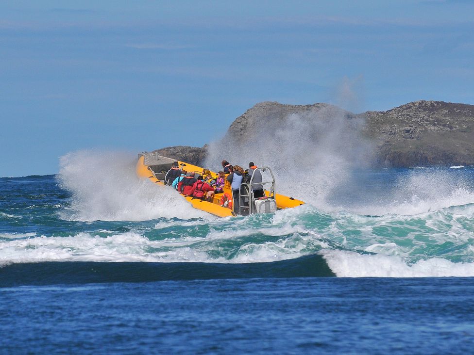 A boat with people navigating waves near an island
