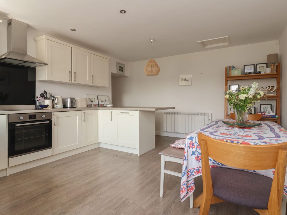 A kitchen with cabinets and a dining table at St Gregory’s Cottage in Oswaldkirk near Helmsley