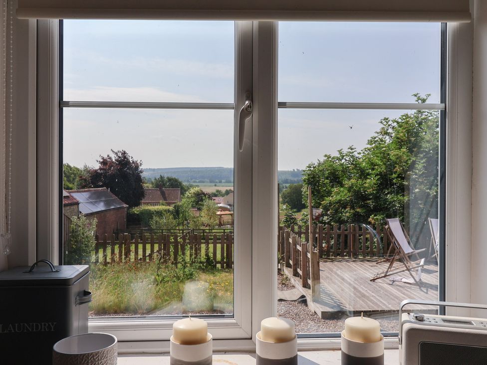 A window view with candles and a garden outside at St Gregory’s Cottage, Oswaldkirk near Helmsley