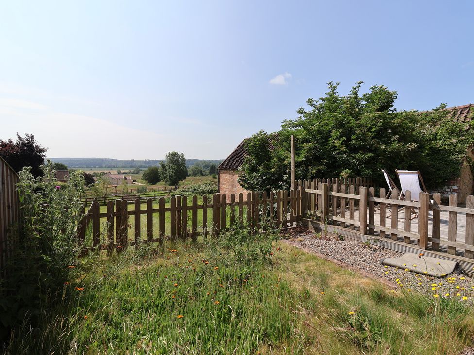 A garden with a fenced area and deck chairs at St Gregory’s Cottage Oswaldkirk near Helmsley