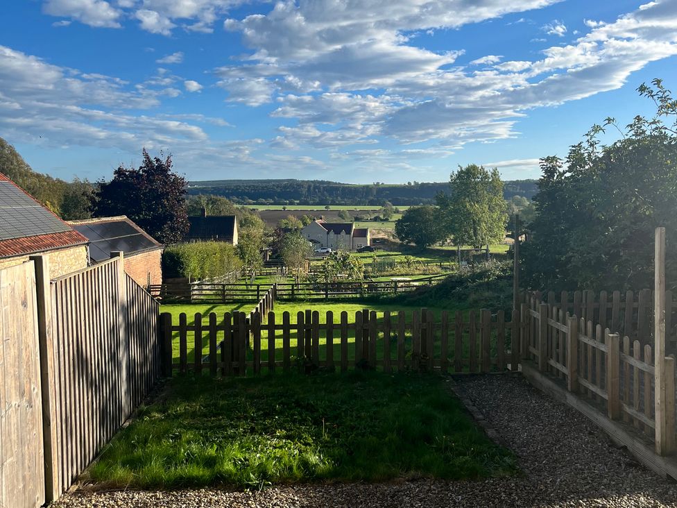 A garden with a fence and view of trees at St Gregory’s Cottage Oswaldkirk near Helmsley