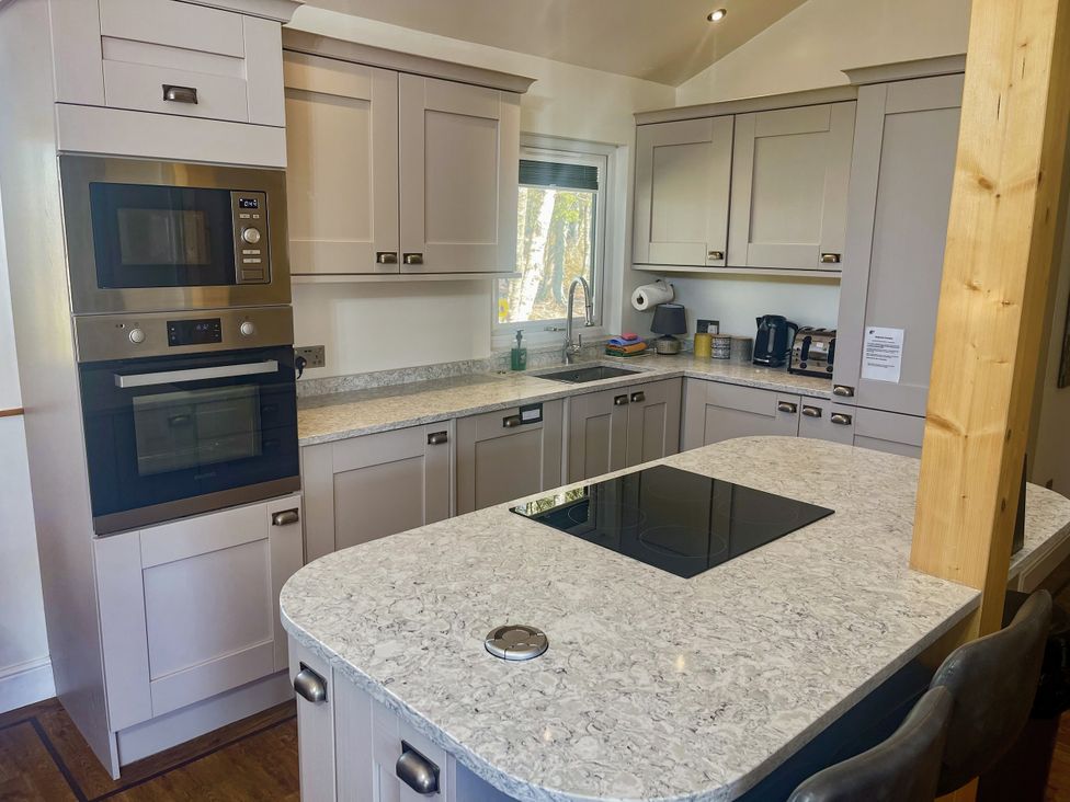 A kitchen with cabinets and appliances at Woodburn Lodge Otterburn