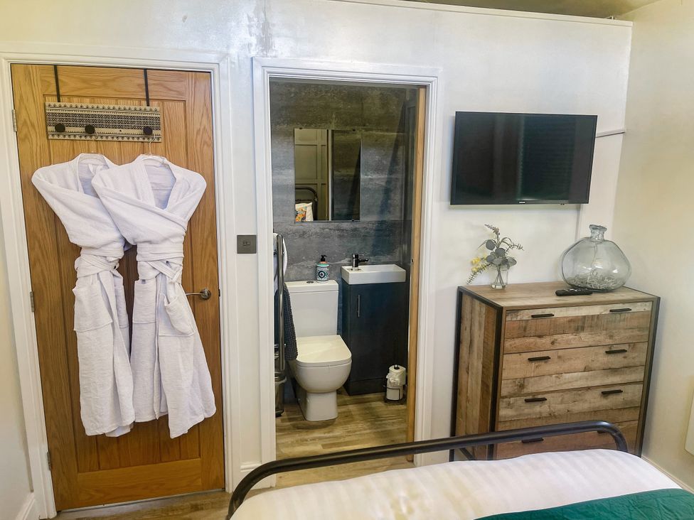 A bedroom with a bathroom and furniture at Woodburn Lodge, Otterburn