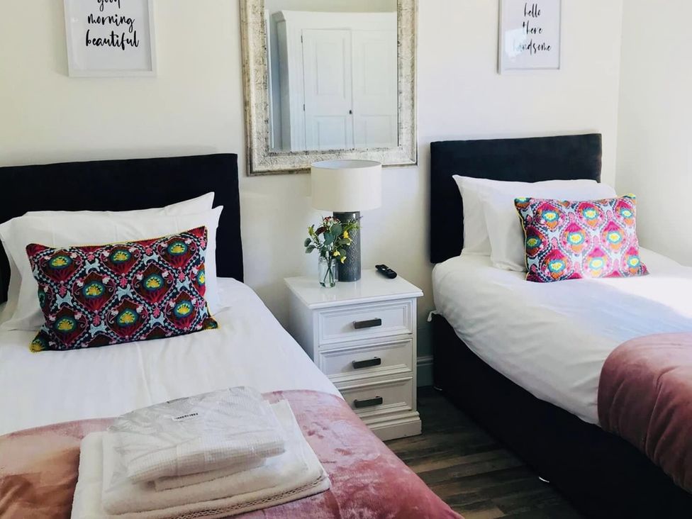 A bedroom with two beds and a nightstand at Woodburn Lodge in Otterburn