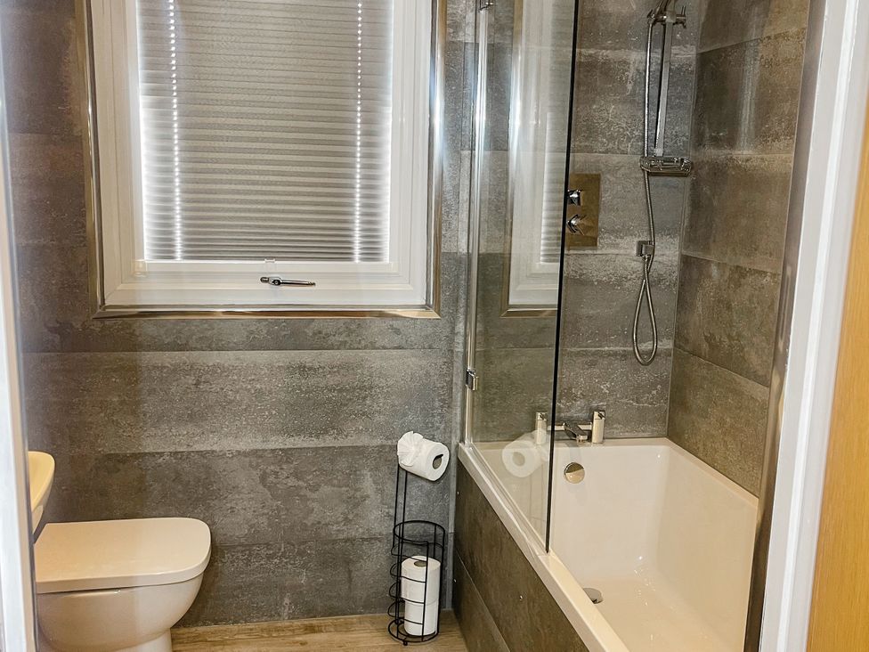 A bathroom with a bathtub and shower at Woodburn Lodge in Otterburn
