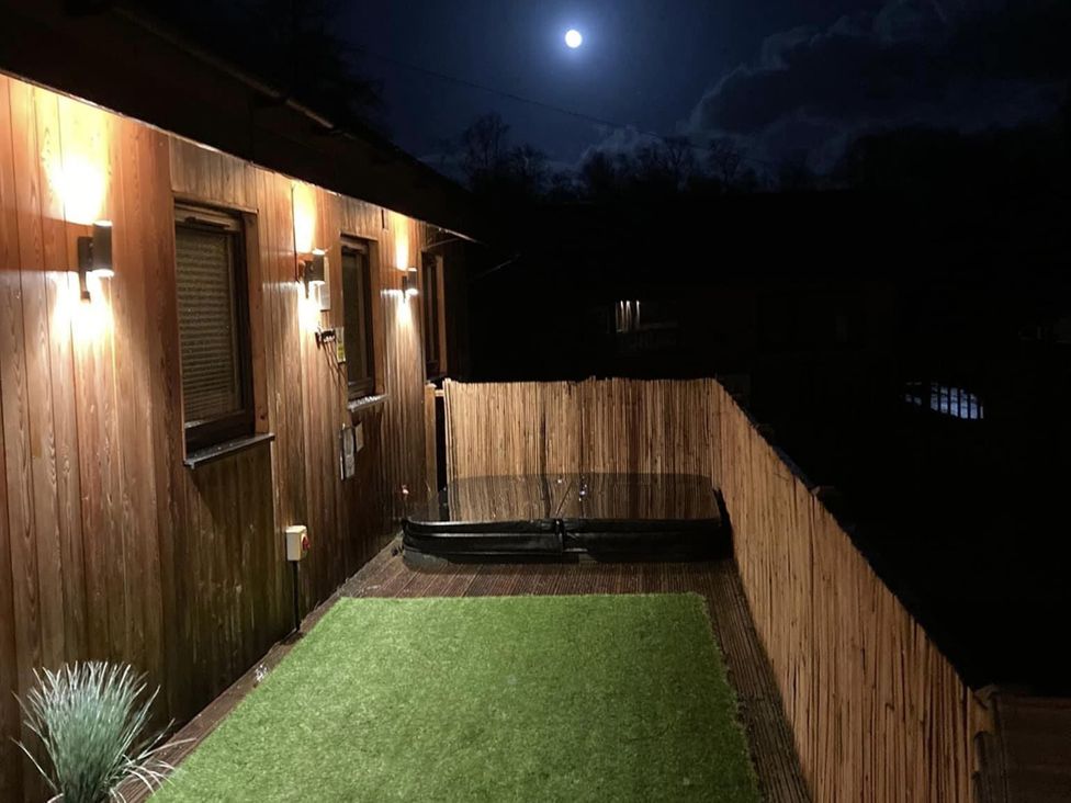 An outdoor area with a hot tub and artificial grass at Woodburn Lodge Otterburn
