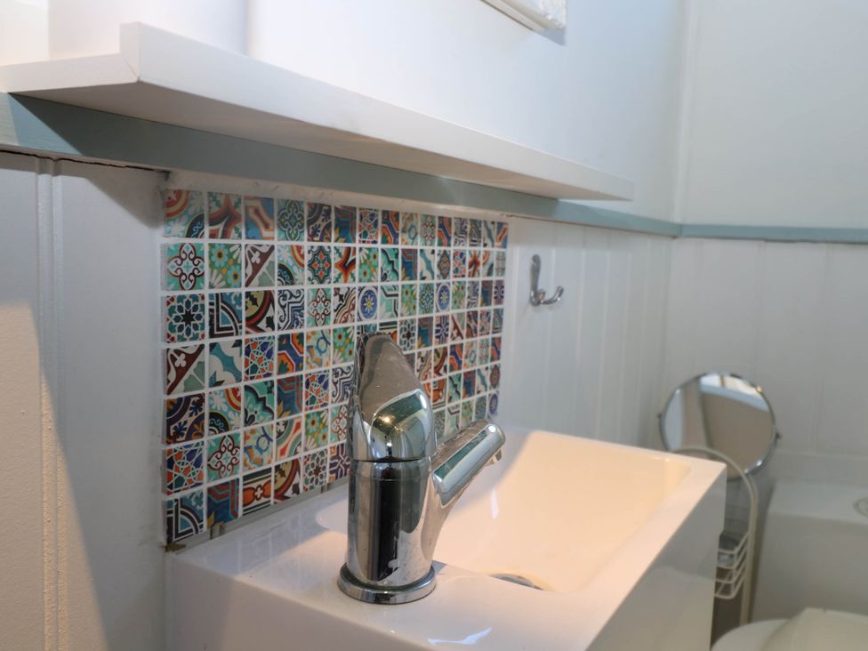 A bathroom sink with a chrome faucet and multicolored backsplash tiles at Songbirds in St Michaels Kent