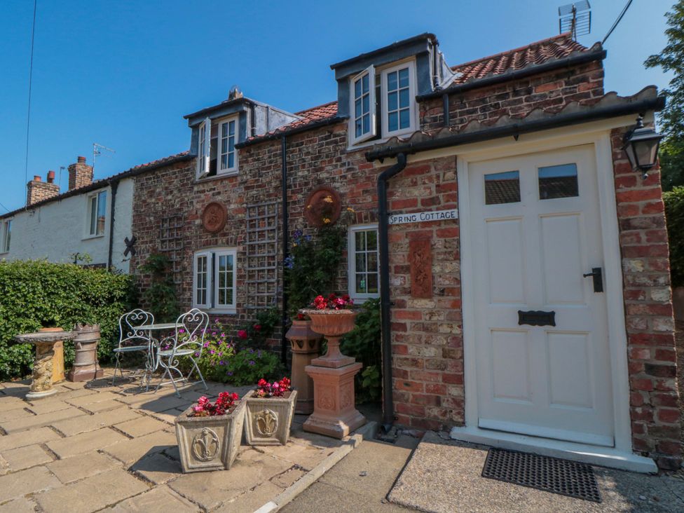 A cottage facade with plants and seating area at Spring Cottage in York