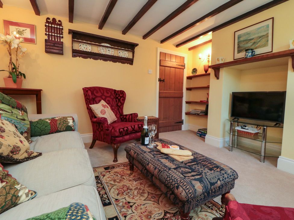 A living room with a red armchair and TV at Spring Cottage in York
