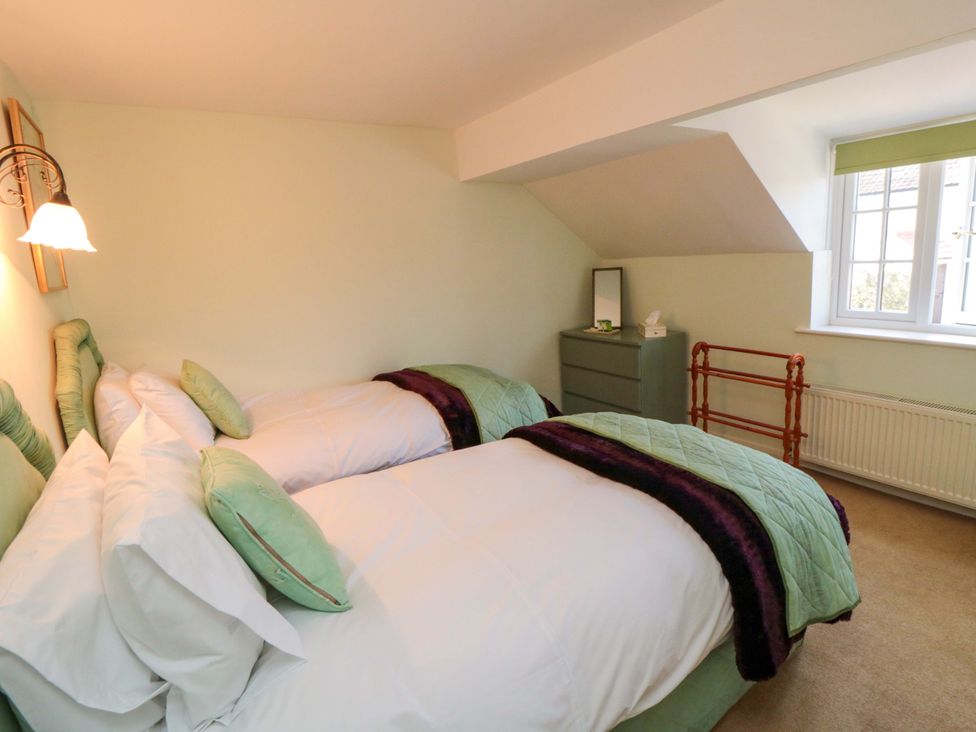 A bedroom with two beds, a mirror and a window at Spring Cottage in York