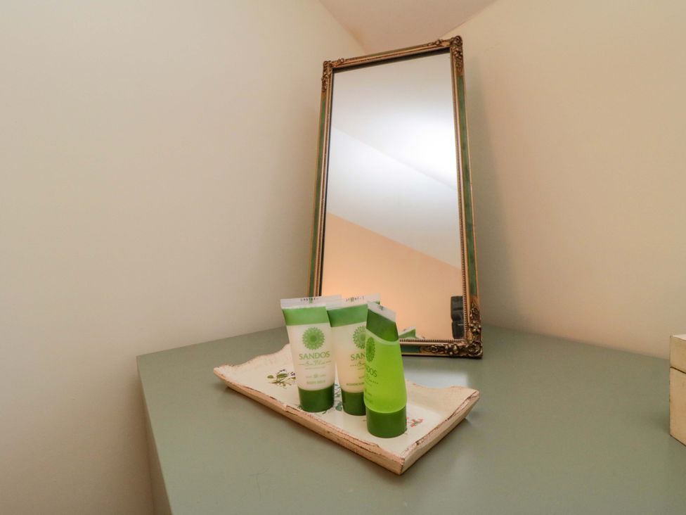 A bathroom countertop with green cream tubes and a mirror at Spring Cottage in York