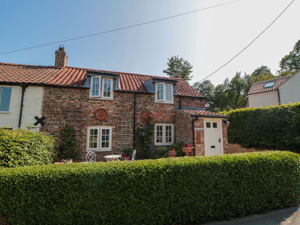 A house with a brick facade and a green hedge at Spring Cottage in York