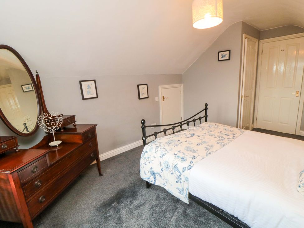 A bedroom with a bed, dresser with mirror, and wall art at The Annex in York