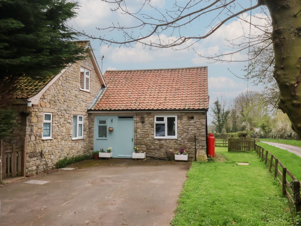 A cottage with a driveway and garden at Walnut Cottage in Helmsley