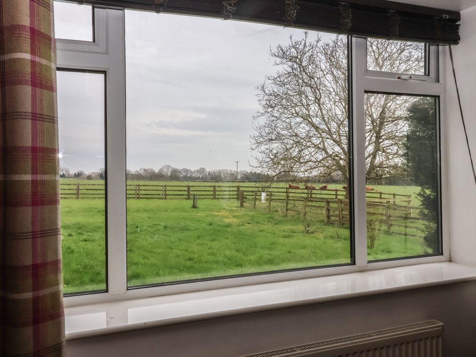 A view of a grassy field and trees from a window at Walnut Cottage in Helmsley