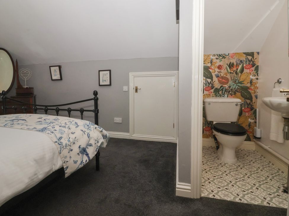 A bedroom with a bed and an adjoining bathroom at Walnut Cottage in Helmsley