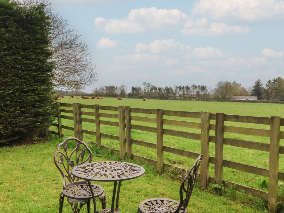 A garden with a table and chairs overlooking a field at Walnut Cottage in Helmsley