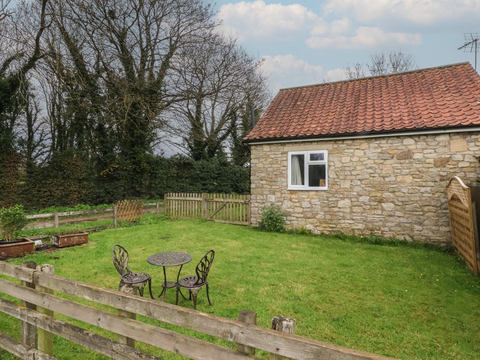 A garden with a table and chairs at Walnut Cottage in Helmsley