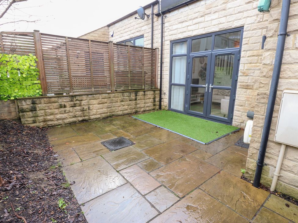 A garden with a patio and sliding door at 12 River View Keighley