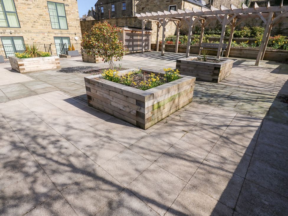 An outdoor garden with planter boxes and a pergola at Loco Lodge in Keighley