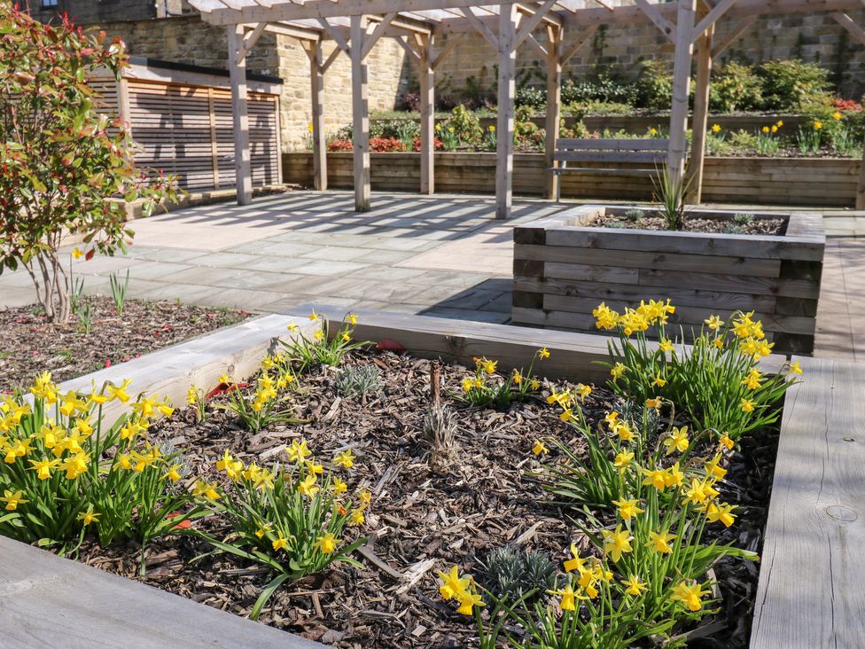 A garden with flowers and wooden structures at Loco Lodge in Keighley