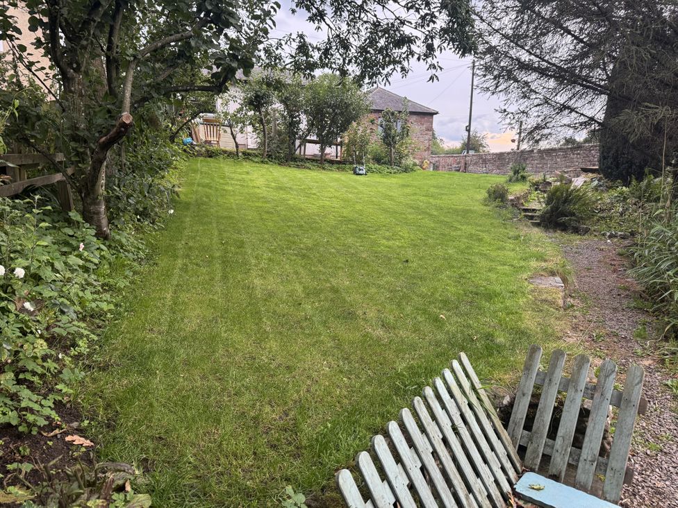 A garden with grass and trees at Yew Tree Cottage