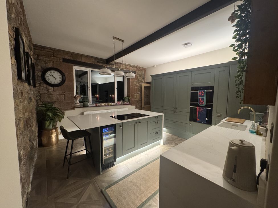 A kitchen with cabinets, a kitchen island, and a sink at Yew Tree Cottage in Mealsgate near Ireby