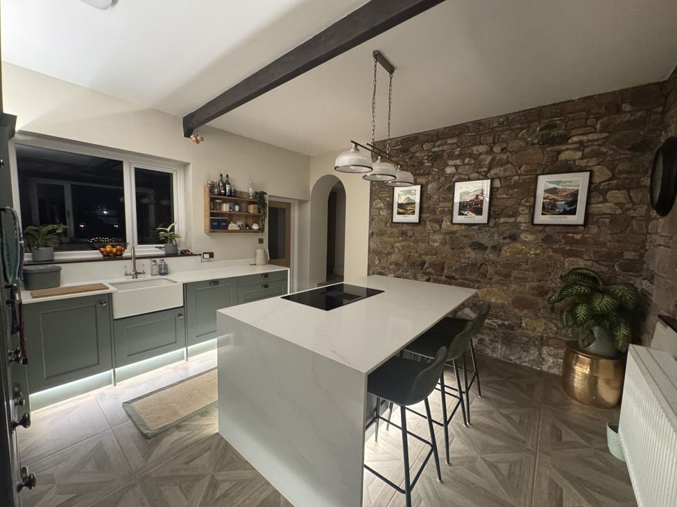 A kitchen with a central island and sink at Yew Tree Cottage in Mealsgate near Ireby